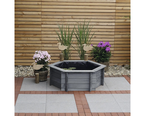 Sechseckiger Teich aus Holz mit Pflanzen und Dekoration im Garten.