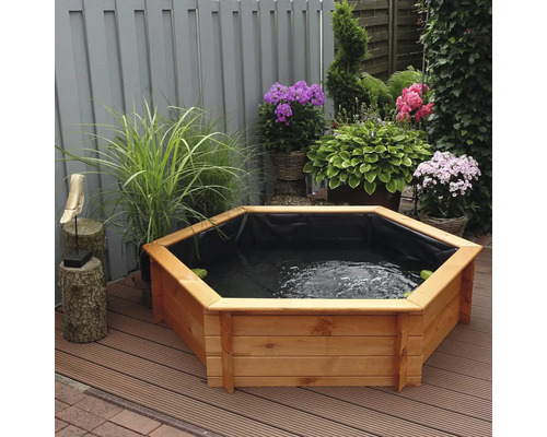 Garten mit einem achteckigen Hochteich aus Holz, bepflanzt mit verschiedenen Blumen und Pflanzen