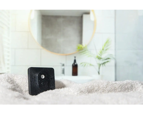 Quadratischer, schwarzer Lufterfrischer auf einem Handtuch im Badezimmer