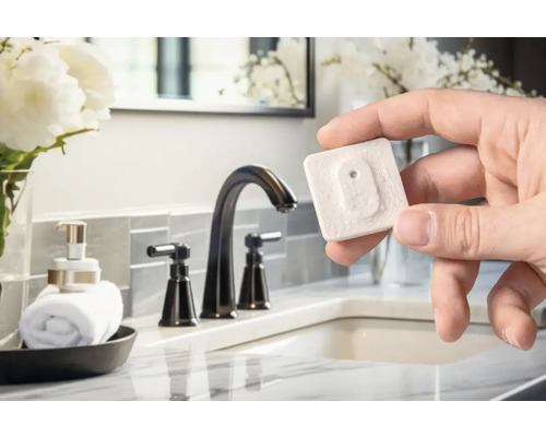 Une main tient un détecteur d''eau dans une salle de bains avec lavabo et robinet