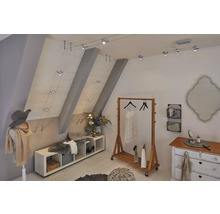 Chambre mansardée avec portant, commode, banc et système de câbles avec projecteurs pour l''éclairage.