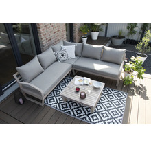 Scène avec un canapé d''angle, une table et un tapis sur une terrasse.