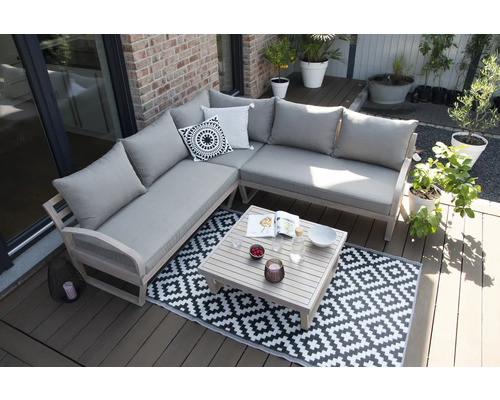 Scène avec un canapé d''angle, une table et un tapis sur une terrasse.
