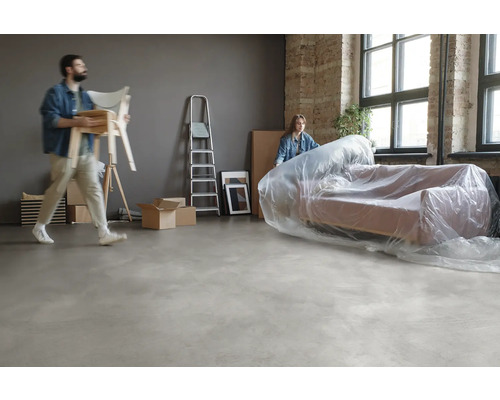 Umzugsszene mit verpacktem Sofa, Stühlen, Leiter und Umzugskartons in einem Raum.