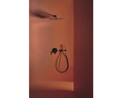 Robinet de douche avec douche de tête, douchette à main et thermostat devant un mur coloré