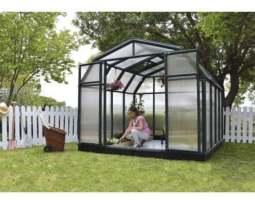 Gewächshaus im Garten mit einer Frau, die Pflanzen pflegt