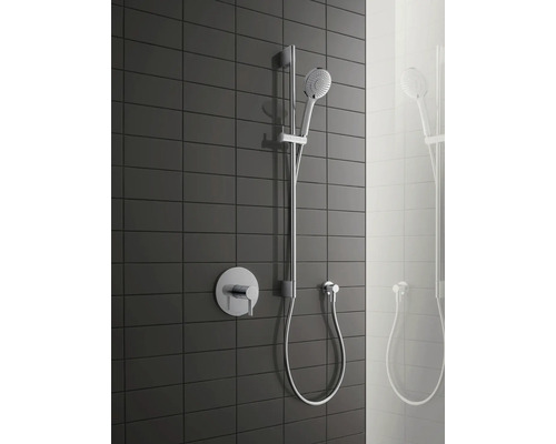 Duschsystem mit Handbrause, Brausestange und Aufputzarmatur vor dunklem Fliesenhintergrund