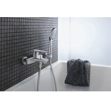 Robinet de salle de bain avec douchette sur un mur avec des carreaux de mosaïque au-dessus d''une baignoire