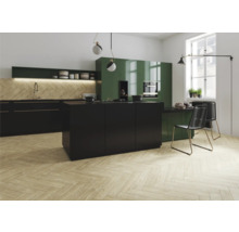 Cuisine claire et spacieuse avec armoires noires et vertes et plancher en bois à chevrons