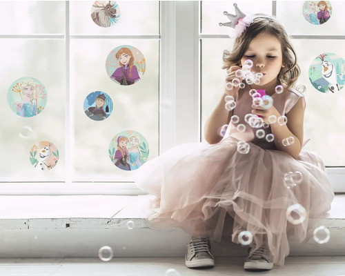 Mädchen mit Krone pustet Seifenblasen vor einem Fenster mit Aufklebern von Die Eiskönigin