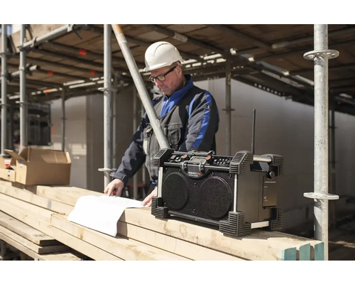 Radio de chantier avec un ouvrier du bâtiment consultant des plans