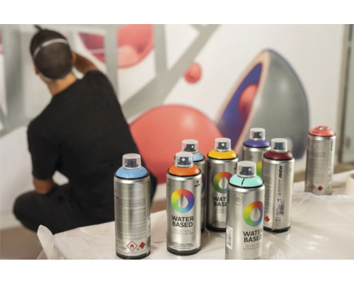 Plusieurs bombes de peinture Montana devant un mur avec un homme qui s''éloigne.