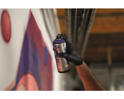 Une personne vaporise de la peinture sur un mur avec un aérosol et crée un graffiti.