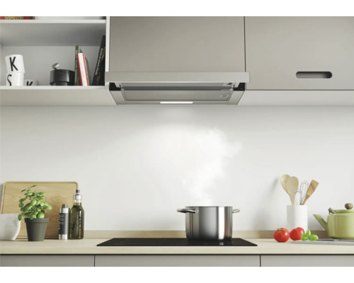 Edelstahl-Dunstabzugshaube über einem Kochfeld in einer hellen Küche.