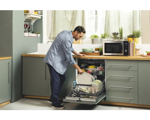 Ein Mann räumt Geschirr in einen Geschirrspüler in einer hellen Küche.