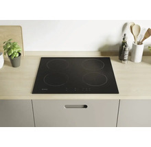 Plaque de cuisson vitrocéramique noire avec quatre zones de cuisson dans une cuisine moderne.
