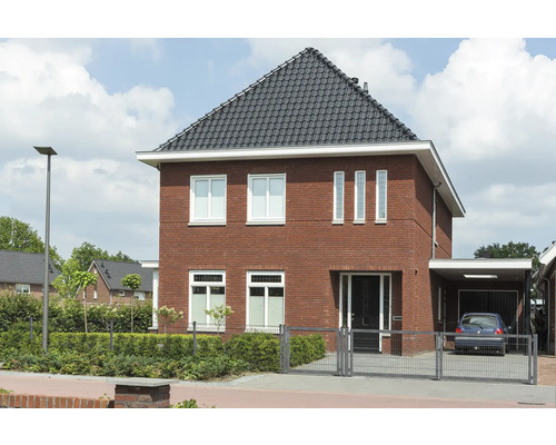 Maison individuelle avec façade en briques, toit en briques foncé et abri de voiture