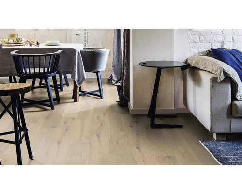 Heller Raum mit Holzboden, Stühlen und Beistelltisch neben einem Sofa.