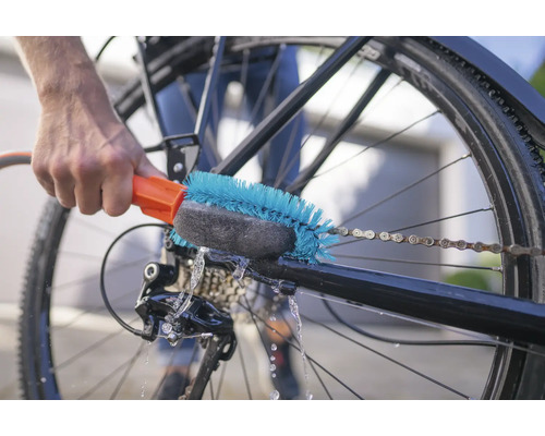Personne nettoie la chaîne de vélo avec une brosse