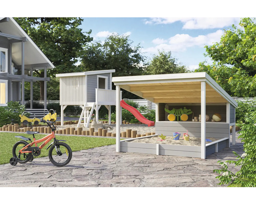 Aire de jeux avec cabane, bac à sable avec toit et vélo pour enfants dans le jardin.