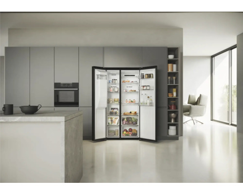 Réfrigérateur-congélateur ouvert dans une cuisine lumineuse avec des armoires de cuisine grises modernes