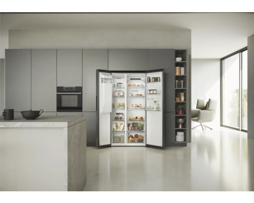 Réfrigérateur combiné américain ouvert dans une cuisine claire avec des armoires grises.
