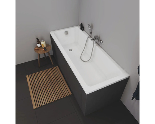 Salle de bains avec baignoire, tapis de bain en bois et table d''appoint