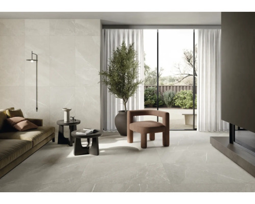 Wohnzimmer mit Fliesenboden und Wandfliesen in Marmoroptik, Sofa, Sesseln und Zimmerpflanze.