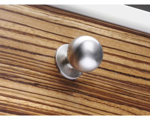 Runder Möbelknopf aus Metall auf einer Holzoberfläche