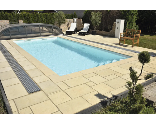 Piscine avec couverture, entourée d''une terrasse en pierre et de mobilier de jardin