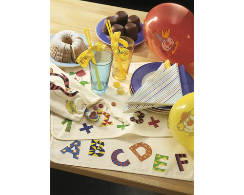 Table décorée avec gâteau, bonbons, boissons, ballons et nappe avec motifs de lettres.