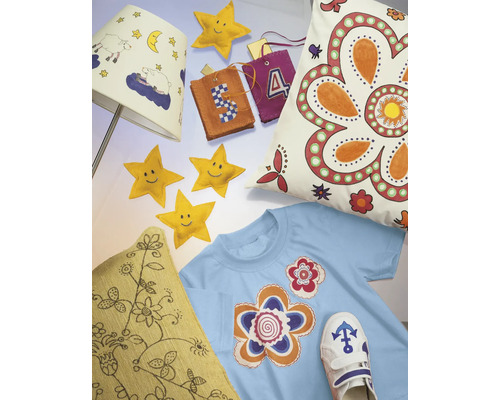 Scène décorative avec un abat-jour, des coussins, un t-shirt, des étoiles et des pendentifs, qui dégage une ambiance chaleureuse et créative.