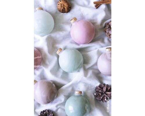 Dekorative Weihnachtskugeln mit Zimtstangen und Zapfen auf Stoff