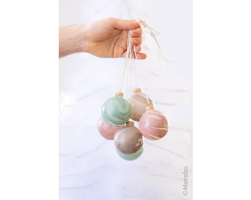 Eine Hand hält sechs marmorierte Weihnachtskugeln an einer Schnur.