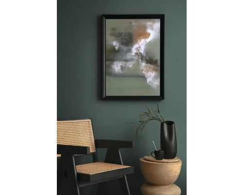 Scène avec une œuvre d''art abstraite encadrée, une chaise en rotin et une table d''appoint avec décoration.