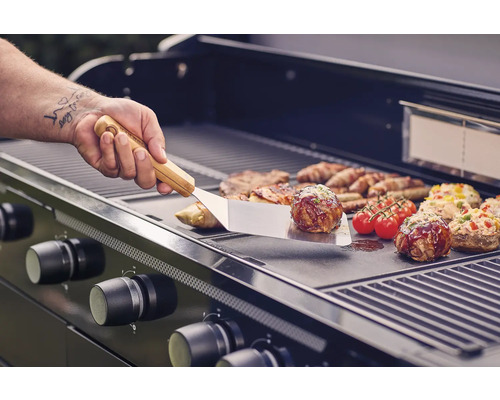 Gril à gaz avec grillades et ustensiles de barbecue en cours d''utilisation