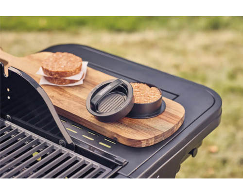 Presse à hamburgers avec deux hamburgers de viande sur une table de grill