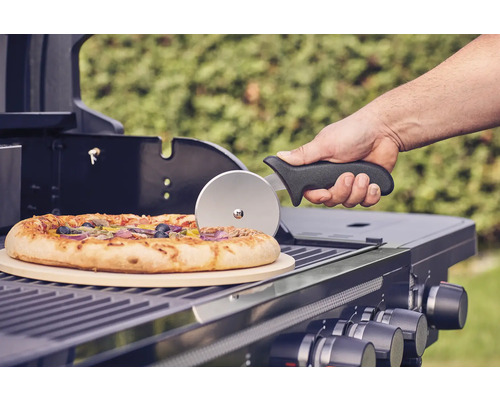 Pizza sur un barbecue avec pierre à pizza et coupe-pizza.