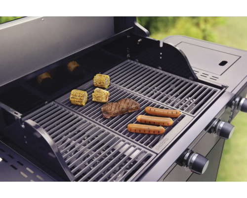 Gril à gaz avec maïs, steak et saucisses sur la grille