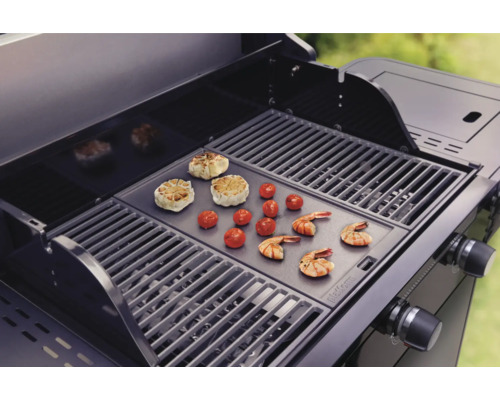 Grill mit Grillgut wie Knoblauch, Tomaten und Garnelen.