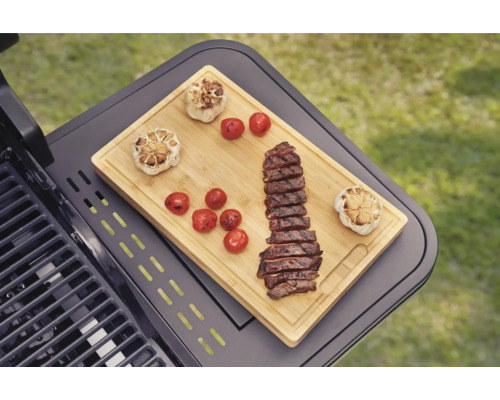 Grill mit Schneidebrett, Knoblauch, Tomaten und geschnittenem Steak