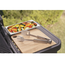 Gemüse in einer Schale, Grillzange und Schneidebrett auf einem Grill