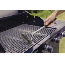 Eine Person reinigt mit einer Grillbürste einen Grillrost.