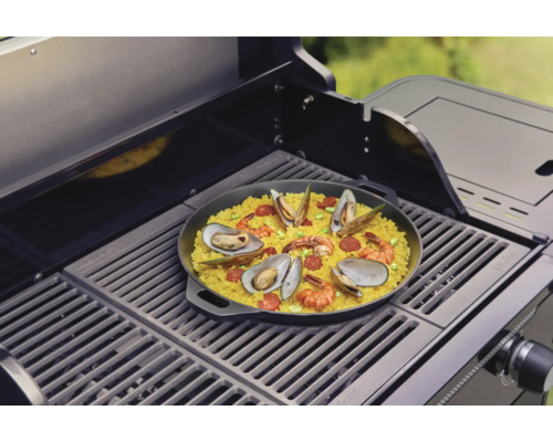 Paella mit Meeresfrüchten auf einem Grill zubereitet.