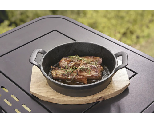 Viande grillée au romarin dans une poêle noire en fonte sur une table en bois