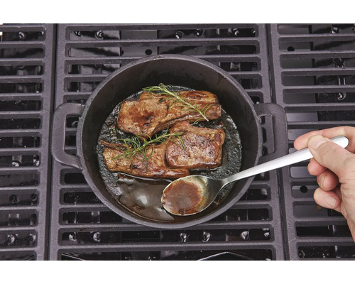 Deux steaks au romarin cuits dans une poêle en fonte sur un barbecue