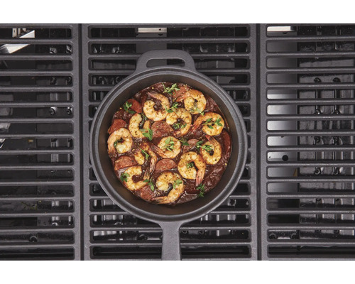 Gusseisenpfanne mit Garnelen und Wurst auf einem Grill