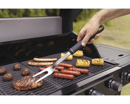Person verwendet Grillgabel auf einem Grill mit verschiedenen Lebensmitteln.