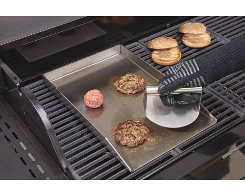 Préparation de hamburgers sur plaque de gril avec spatule et pains à hamburgers