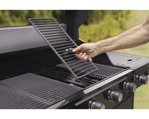 Eine Person legt einen Grillrost in einen Gasgrill.